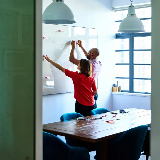 Two people in office drawing on whiteboard Facebook for agencies