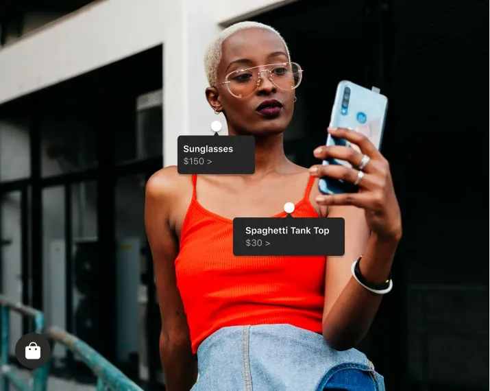a Shop example showing a woman on her phone – sell more merch to your fans online through Facebook and Instagram