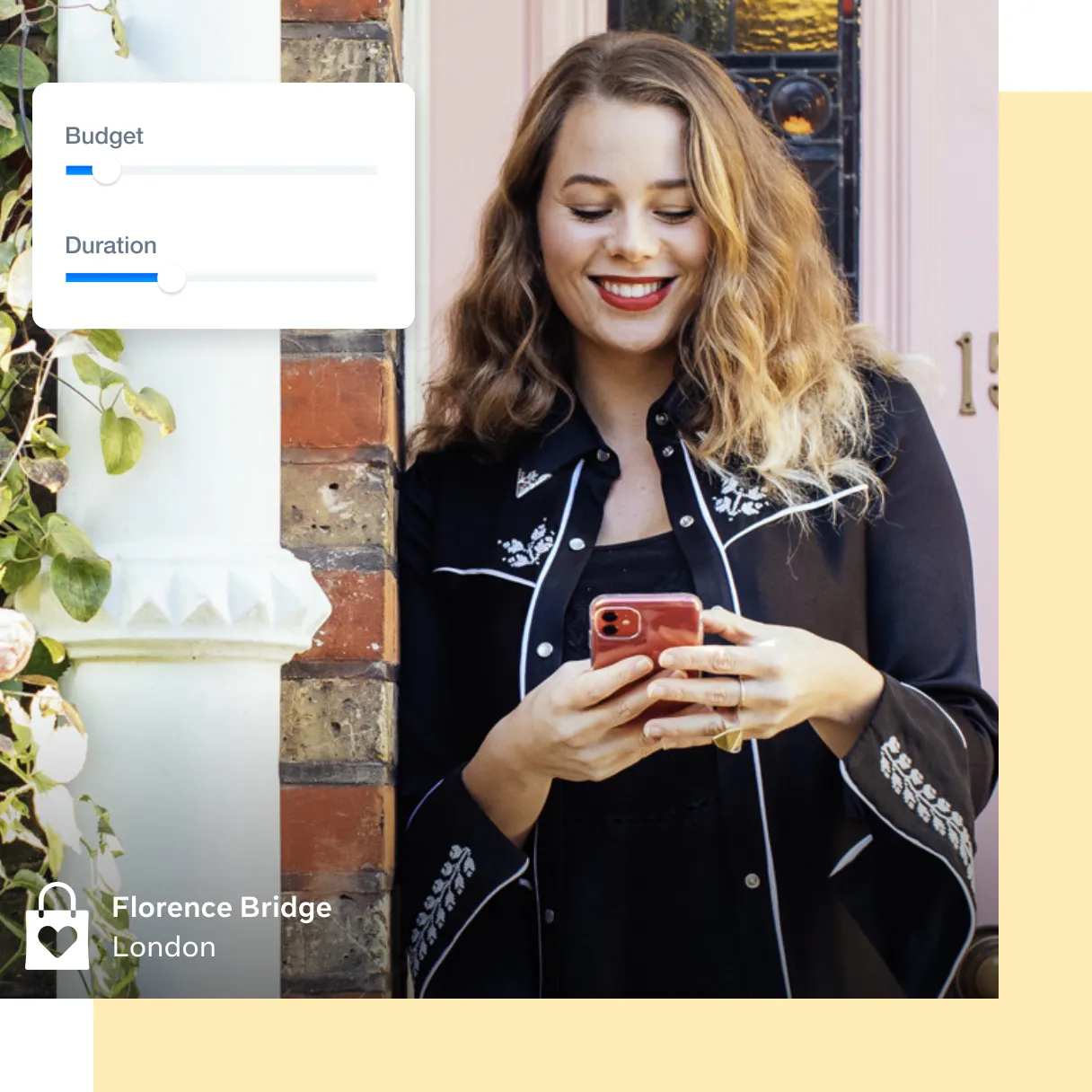 woman outside leaning on a wall smiling while looking at her phone