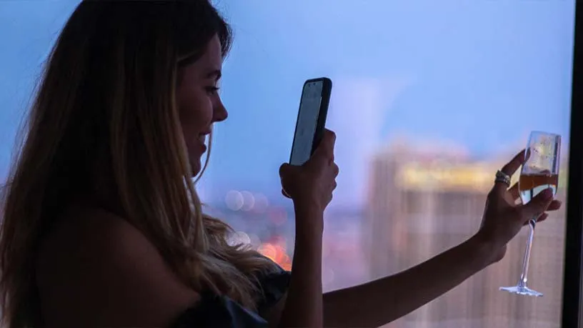 Woman taking picture of wine in front of a window at an MGM resort