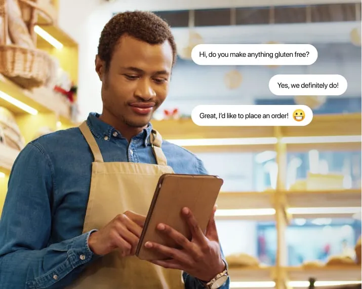 Man wearing apron and working in a bakery uses chat to communicate with customer.