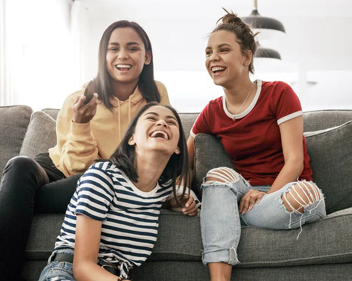 Three young women sitting on a sofa while watching television