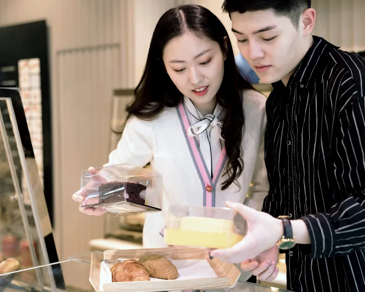 Two people in a brightly lit cafe looking over some pre-packaged goods